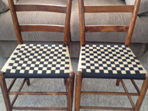 Two wooden, wicker chairs with checkered shaker tape seat weaving