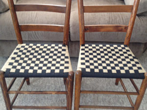 Two wooden, wicker chairs with checkered shaker tape seat weaving